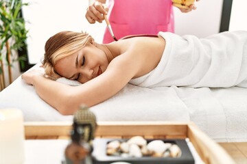 Obraz na płótnie Canvas Young caucasian woman lying on table having back chocolate treatment at beauty salon
