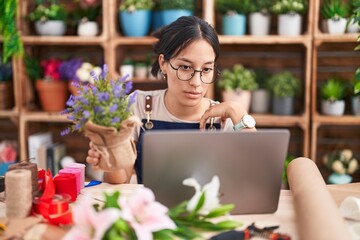 Young hispanic woman working at florist shop doing video call looking sleepy and tired, exhausted...