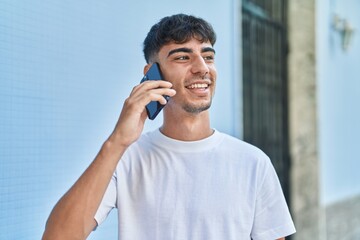 Young hispanic man smiling confident talking on the smartphone at street