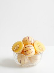 Vertical shot of fresh pepino melons in glass bowl on white table
