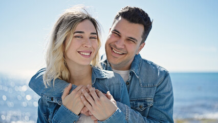 Man and woman couple smiling confident hugging each other at seaside