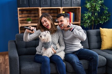 Man and woman singing song sitting on sofa with dog at home