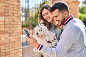 Man and woman holding dog having video call by smartphone at street