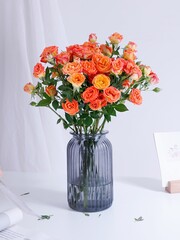 Vertical shot of a beautiful bouquet of roses in a blue glass vase on a white table