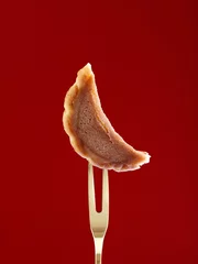 Zelfklevend Fotobehang Closeup of a cookie slice on a fork in a maroon background © Jingluo/Wirestock Creators