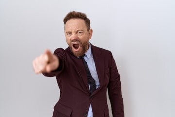 Middle age business man with beard wearing suit and tie pointing displeased and frustrated to the camera, angry and furious with you