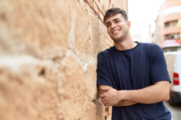 Young hispanic man standing with arms crossed gesture at street