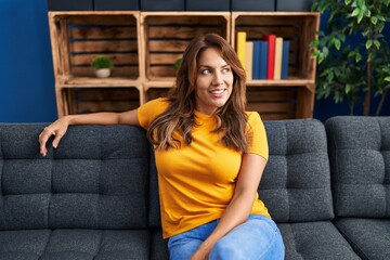 Obraz premium Young latin woman smiling confident sitting on sofa at home