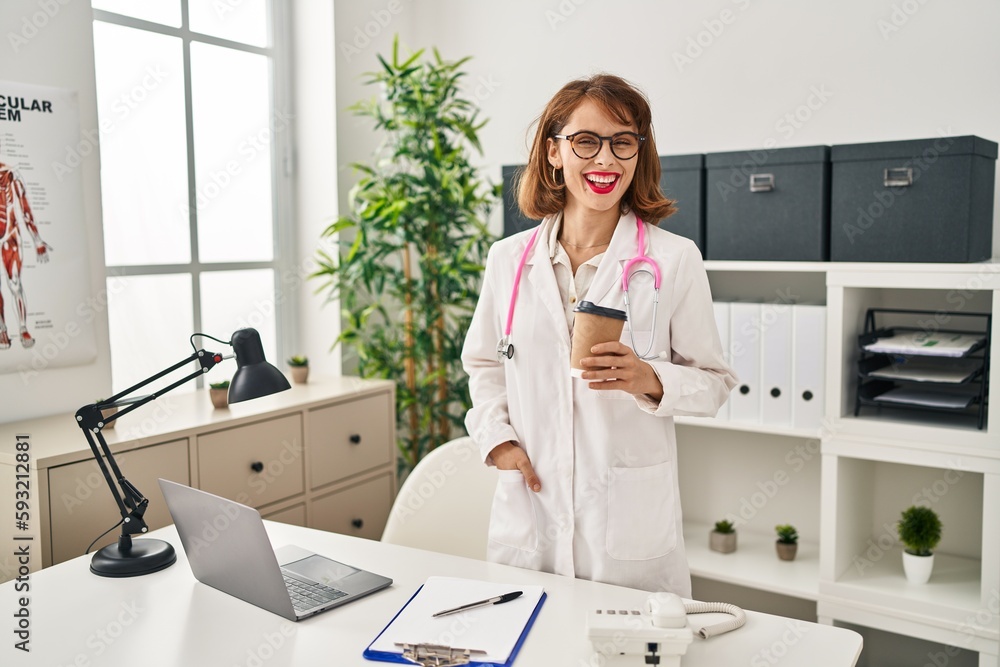 Sticker Young caucasian woman wearing doctor uniform drinking coffee at clinic