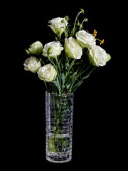 Vertical shot of a bouquet of white roses in a vase isolated on a dark background