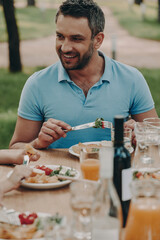 Happy young man enjoying meal while having dinner outdoors