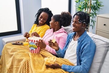 African american friends watching movie sitting on sofa at home
