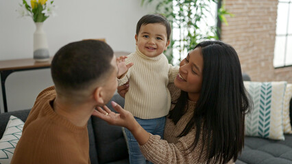 Couple and son hugging each other sitting on sofa at home