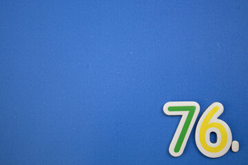 Placed on the edge of the blue background, photographed from above, the number 76.