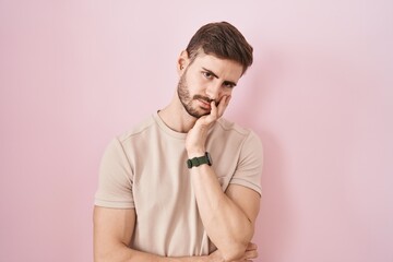 Hispanic man with beard standing over pink background thinking looking tired and bored with depression problems with crossed arms.