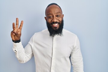 African american man standing over blue background showing and pointing up with fingers number three while smiling confident and happy.