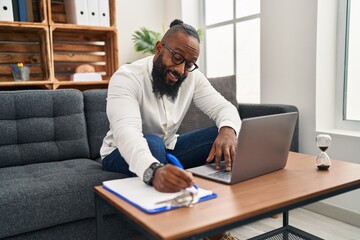 Naklejka premium Young african american man psychologist using laptop at psychology center