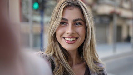 Young blonde woman smiling confident making selfie by camera at street