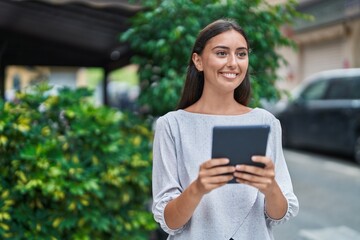 Young beautiful hispanic woman smiling confident using touchpad at street