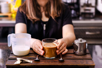 Pouring milk into coffee making espresso. Professional barista preparing coffee on counter.