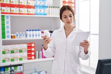 Young woman pharmacist reading prescription holding pills at pharmacy