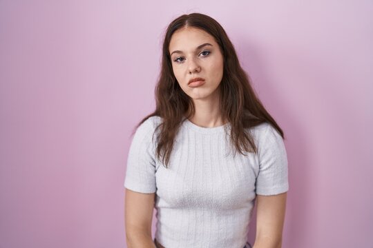 Young hispanic girl standing over pink background looking sleepy and tired, exhausted for fatigue and hangover, lazy eyes in the morning.