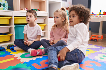 Obraz premium Group of kids sitting on floor with relaxed expression at kindergarten