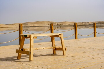 Empty wooden bench on the dock against the background of the lake.