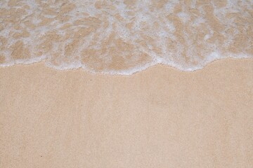 Top view of sea waves on a sandy beach.