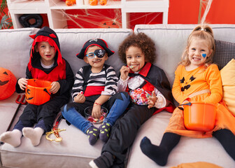 Group of kids wearing halloween costume eating candies at home