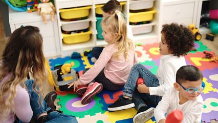Woman and group of kids playing with tools toy sitting on floor at kindergarten
