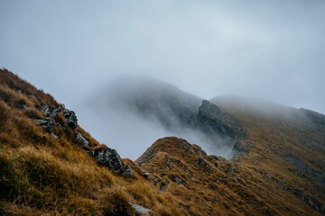 Scenic view of a mountain range covered with clouds on a foggy day