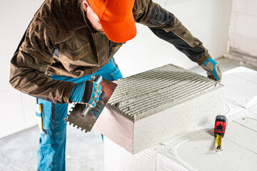 Construction work. Applying mortar with a toothed trowel to the insulation block. Internal...