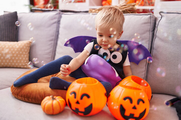 Fototapeta premium Adorable caucasian boy wearing halloween costume playing with soap bubbles at home