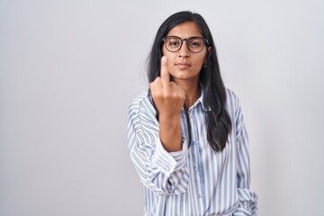 Young hispanic woman wearing glasses showing middle finger, impolite and rude fuck off expression