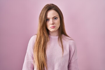 Young caucasian woman standing over pink background depressed and worry for distress, crying angry...