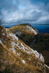 Vertical shot of the rocky peaks of the mountain with the gloomy cloudy sky in the background
