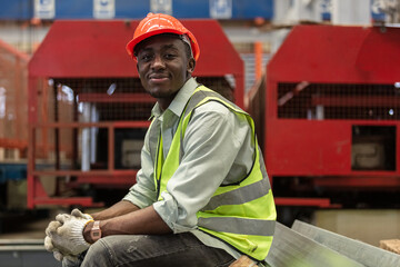 portrait engineering male African American workers wear red helmet sitting at machine area in...