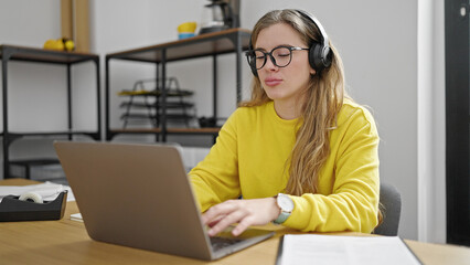 Young blonde woman business worker using laptop and headphones working at office