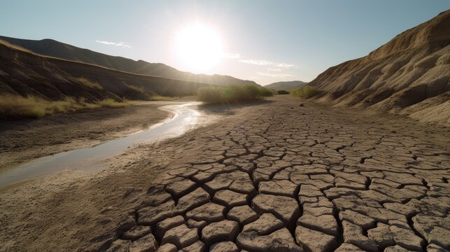 A picture of a dry river bed with cracked mud and no water.
