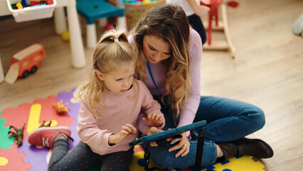 Woman and girl having lesson using touchpad at kindergarten