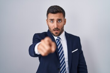 Handsome hispanic man wearing suit and tie pointing displeased and frustrated to the camera, angry and furious with you