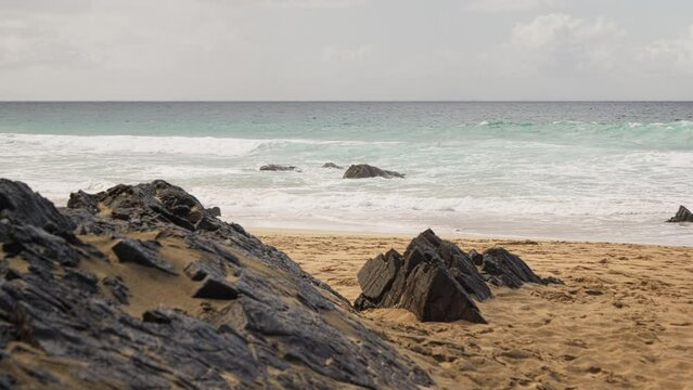 Wild beach, big rocks, waves crashing on the shore