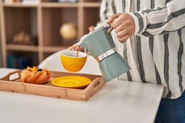 Young chinese woman having breakfast pouring coffee at home