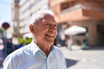 Middle age grey-haired man smiling confident looking to the side at street