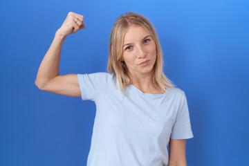 Fototapeta premium Young caucasian woman wearing casual blue t shirt strong person showing arm muscle, confident and proud of power