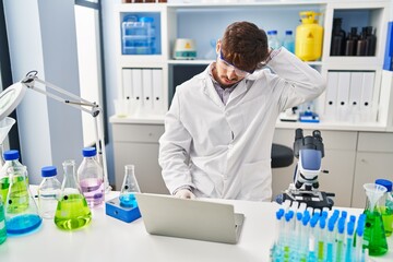 Young arab man scientist stressed using laptop working at laboratory