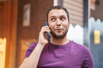 Young man smiling confident talking on the smartphone at street