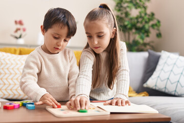 Fototapeta premium Adorable boy and girl playing with maths puzzle game standing at home