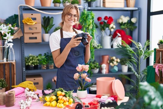 Young blonde girl florist making photo to flowers at florist